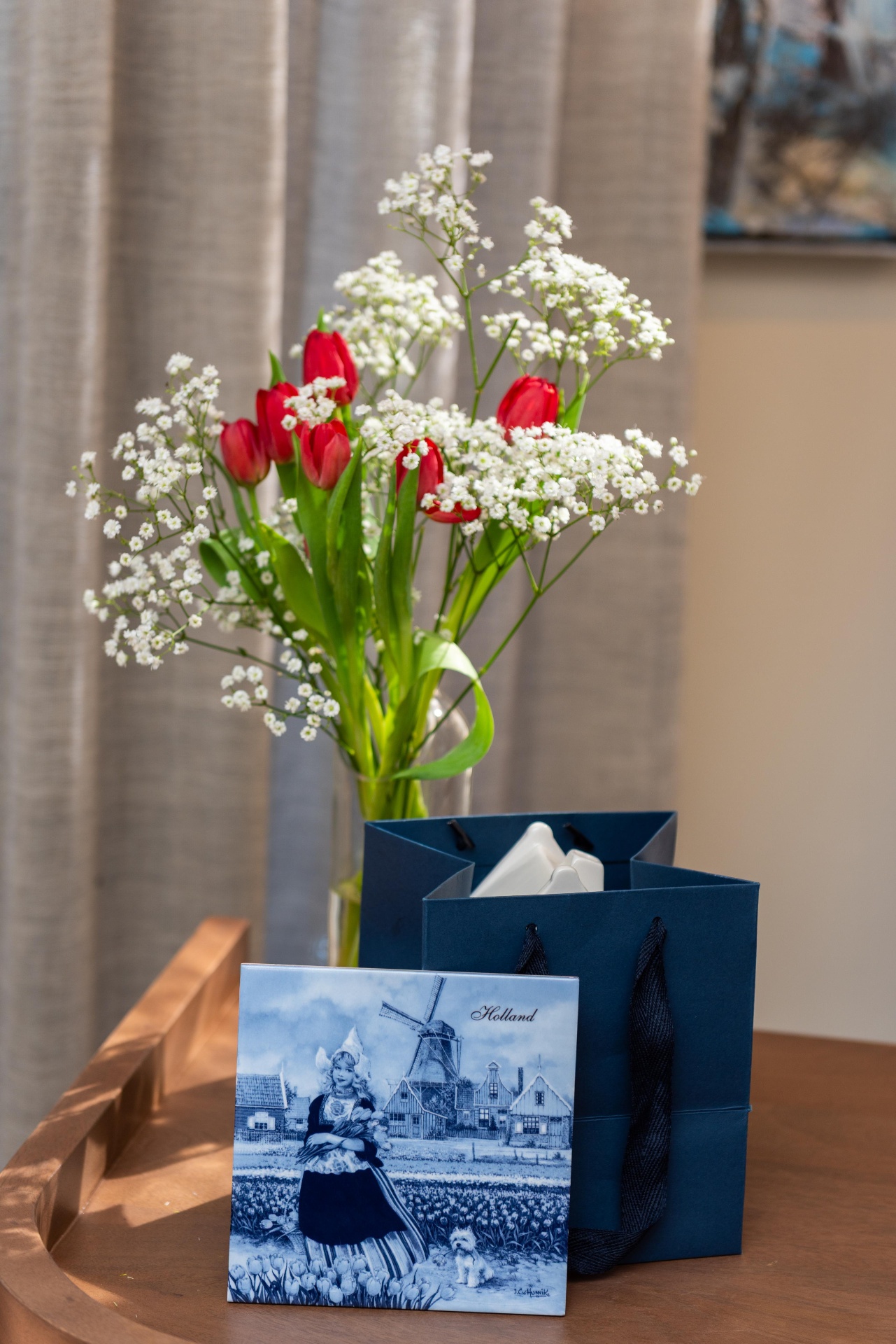 Red tulips with baby's breath beside a hand-painted Delft blue Holland tile at Dutch Masters Studio